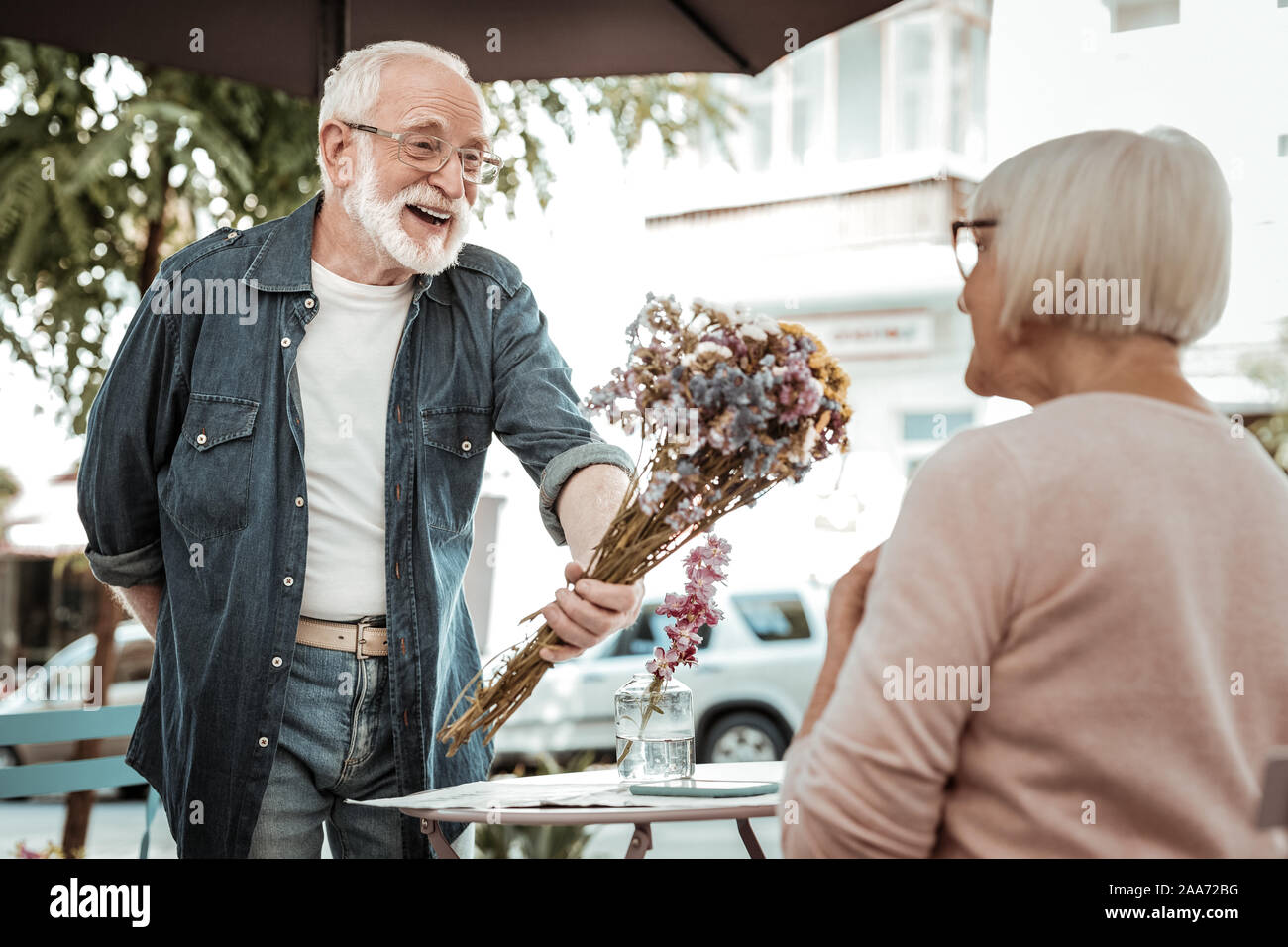 Positive bearded man giving a flower bouquet Stock Photo