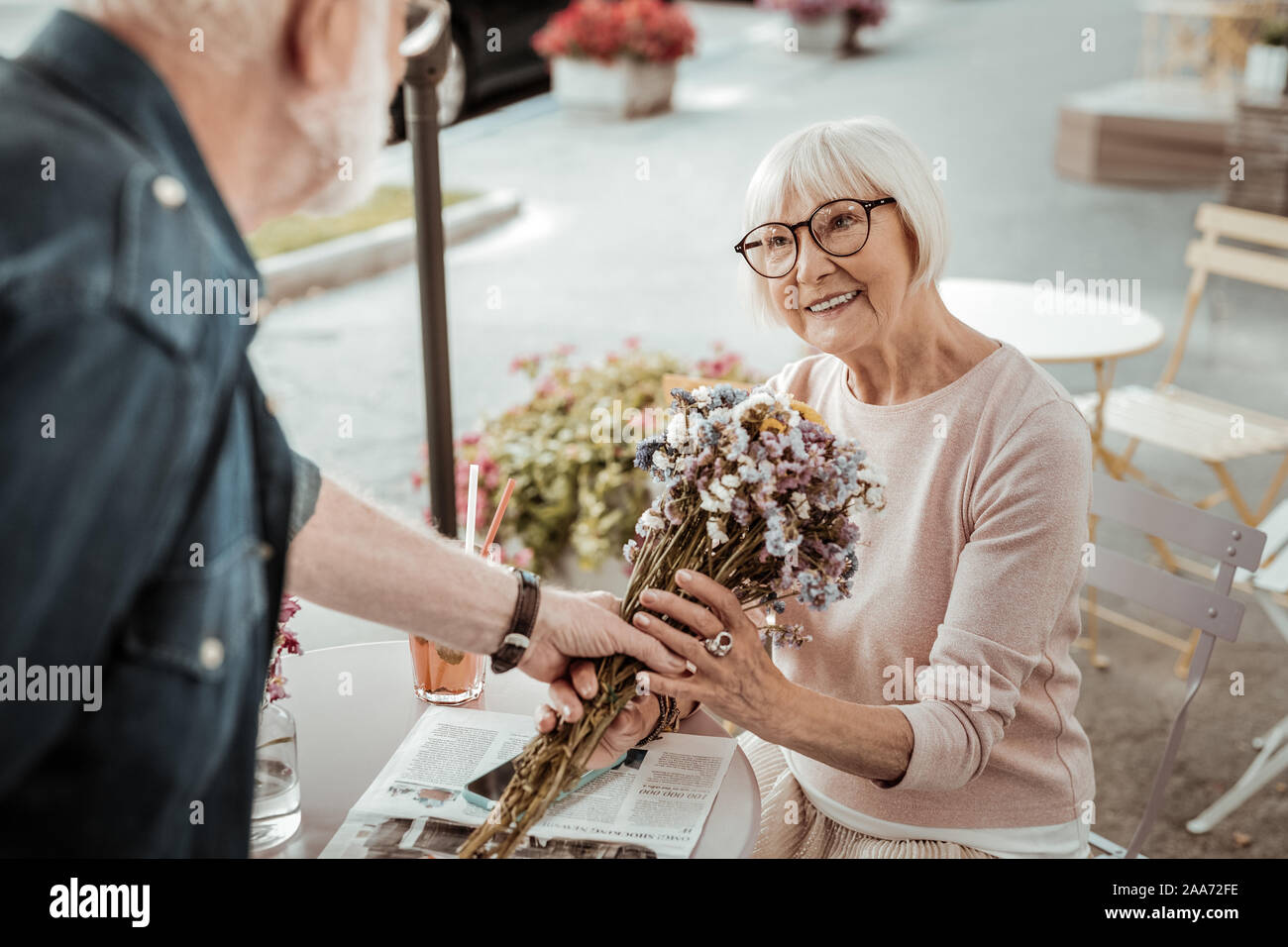 Happy nice aged woman receiving beautiful flowers Stock Photo