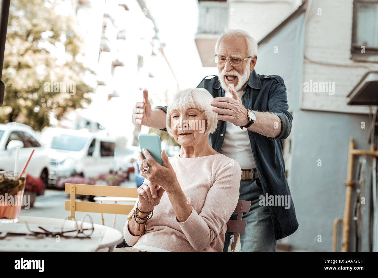 Nice happy aged man standing behind his wife Stock Photo