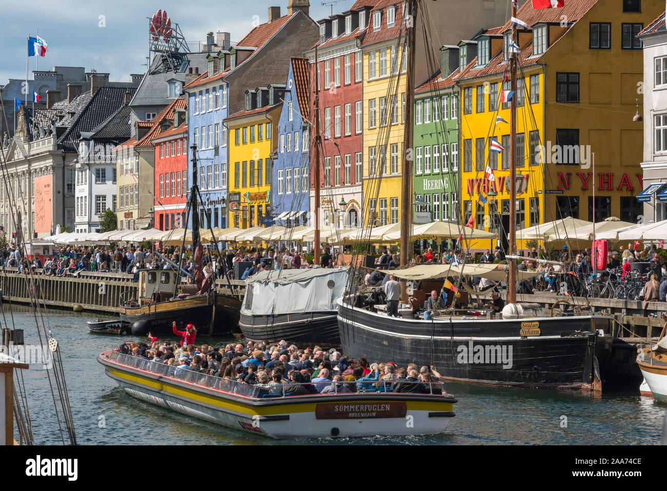 Nyhavn Copenhagen, view in summer of the popular Nyhavn waterfront area with a group of tourists on a boat tour of the Copenhagen canals, Denmark. Stock Photo