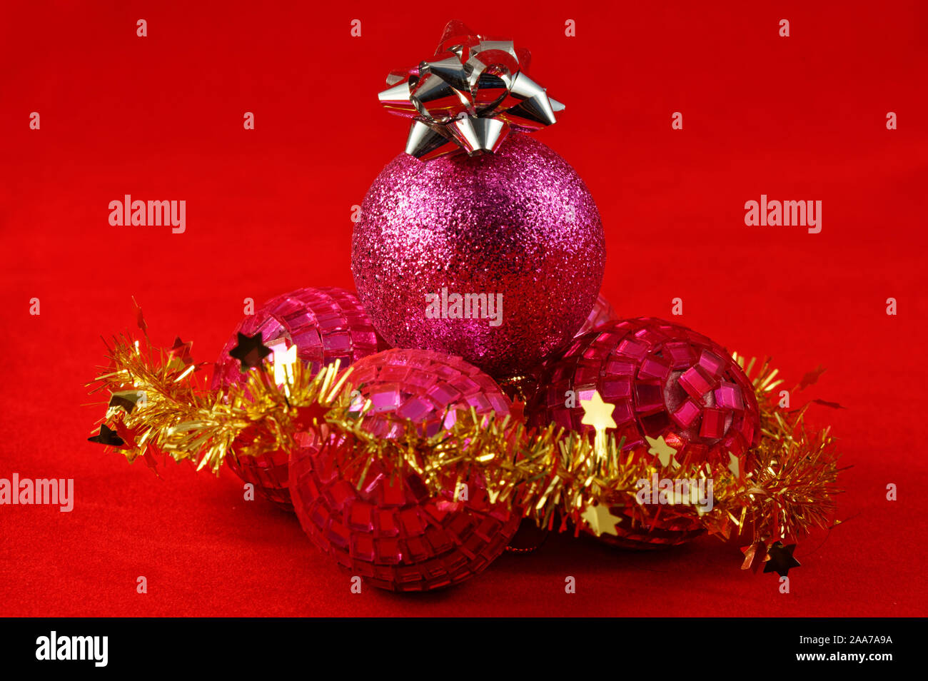 Purple and pink round Christmas baubles with a silver star on top and gold tinsel in front Stock Photo