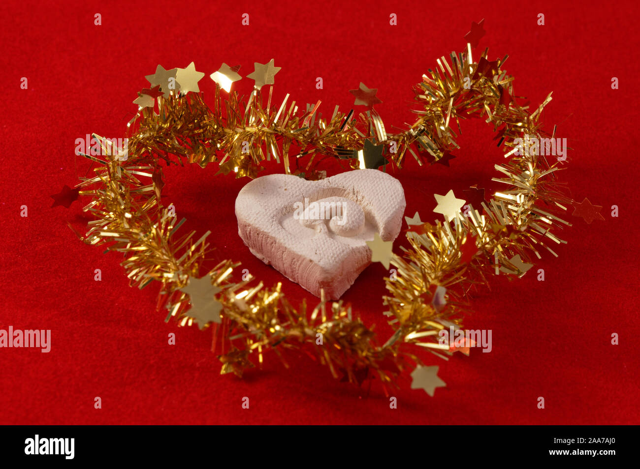 A hand crafted heart is surrounded by gold tinsel Stock Photo