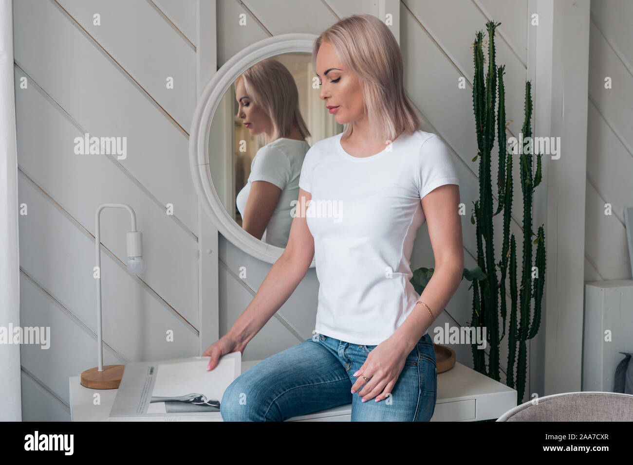 Delicate portrait of a beautiful blonde in a white t-shirt and blue jeans Stock Photo