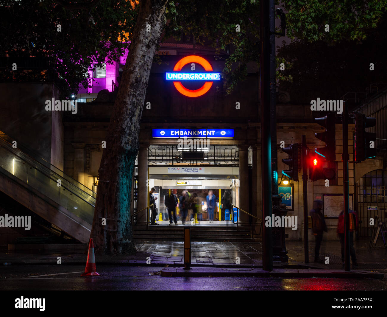 London, England, UK - October 14, 2019: Commuters walk through London's Embankment Station lit up at night. Stock Photo