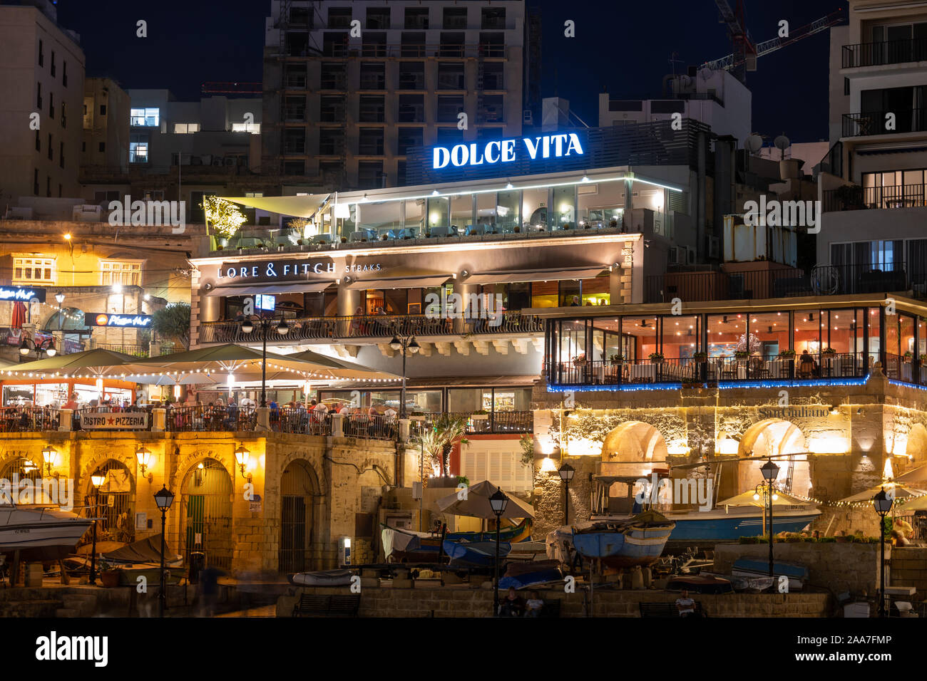 Paceville, St Julian, Malta - October 10, 2019: Restaurants Dolce Vita, Lore and Fitch and San Giuliano in Paceville, Saint Julian town at night Stock Photo