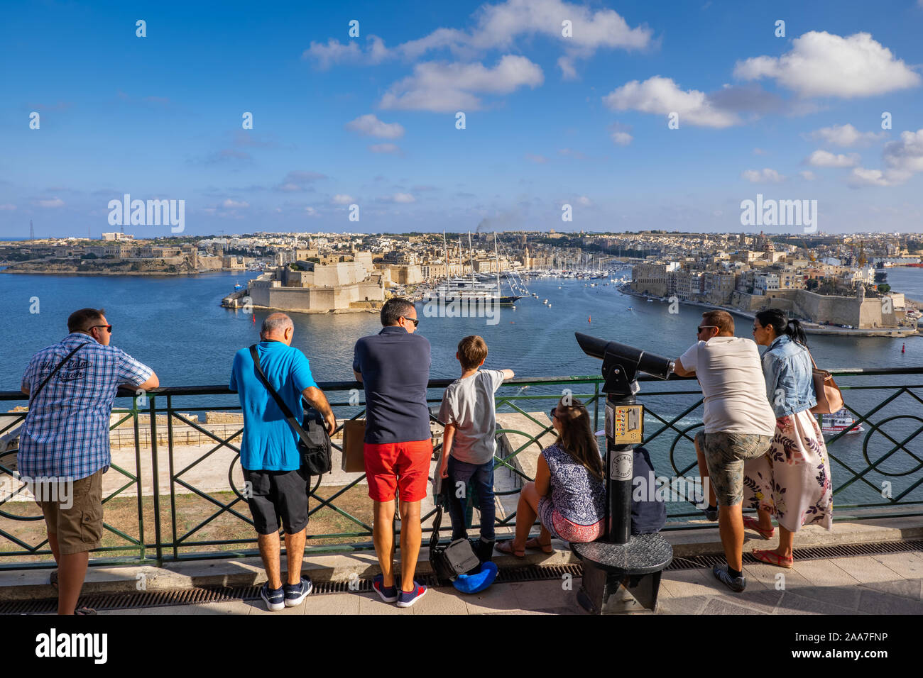 Valletta, Malta - October 13, 2019: Group of tourists enjoying the view of the Three Cities and Grand Harbour from Upper Barrakka Gardens viewpoint in Stock Photo