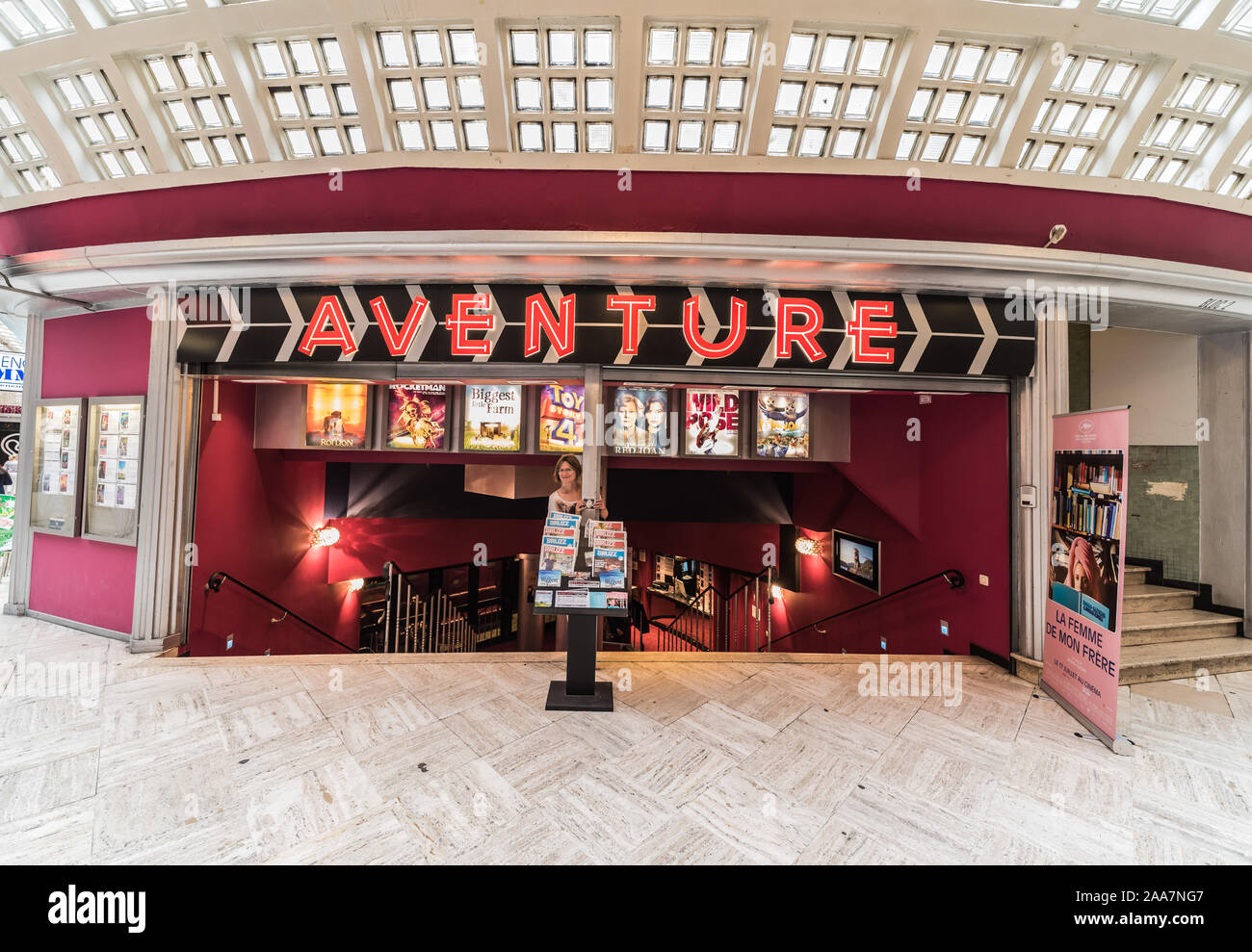 Brussels Old Town / Belgium - 07 18 2019: Young woman standing in front of the entrance of the Adventure vintage cinema Stock Photo