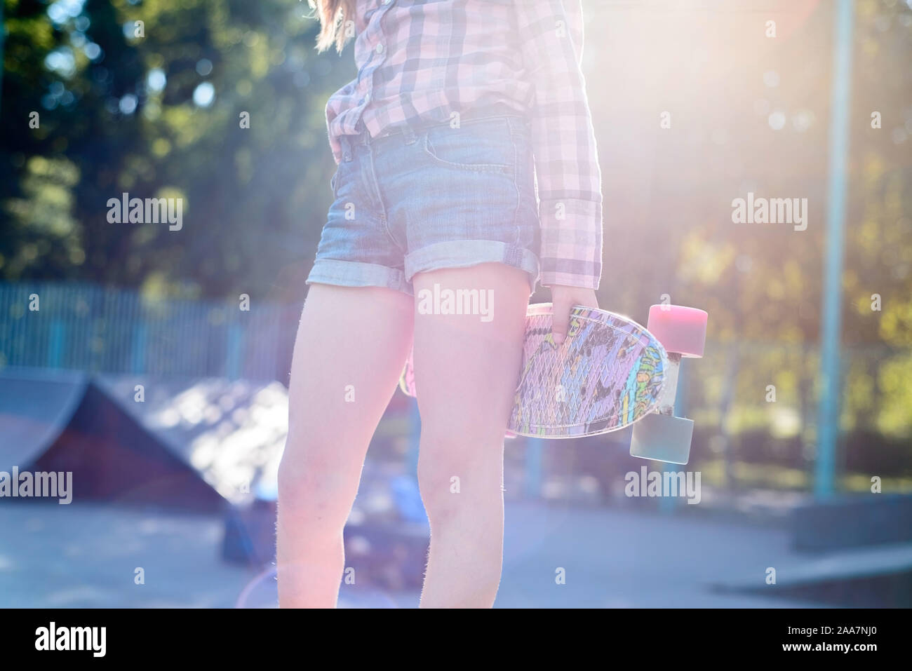 Skater female rides on skateboard at skate park ramp. Young woman practising skateboarding