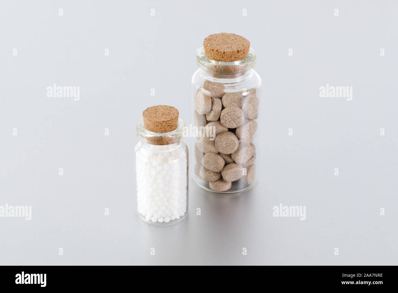natural medicine bottles with herbal pills and globules on gray background Stock Photo