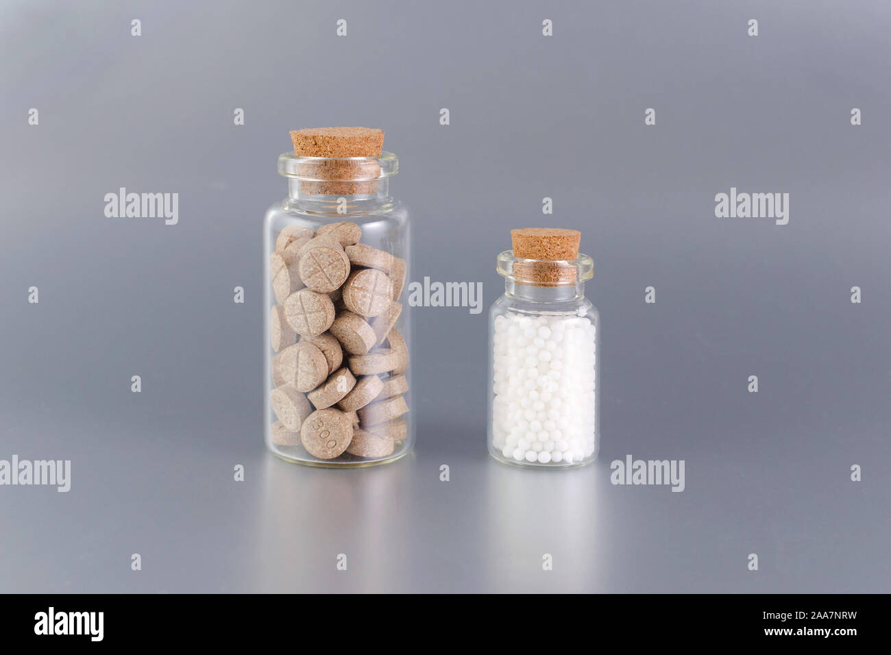 natural medicine bottles with herbal pills and globules on gray background Stock Photo