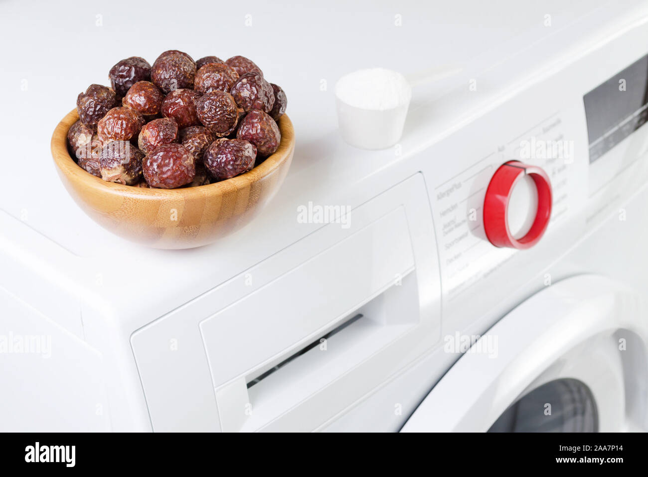 soap nuts in a bowl on the washing machine and detergent powder, selective focus Stock Photo