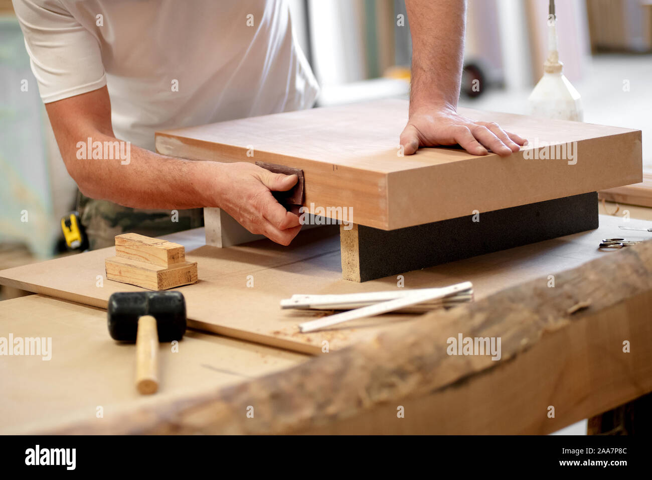 Carpenter Sanding A Wooden Block On A Workbench In A Woodworking