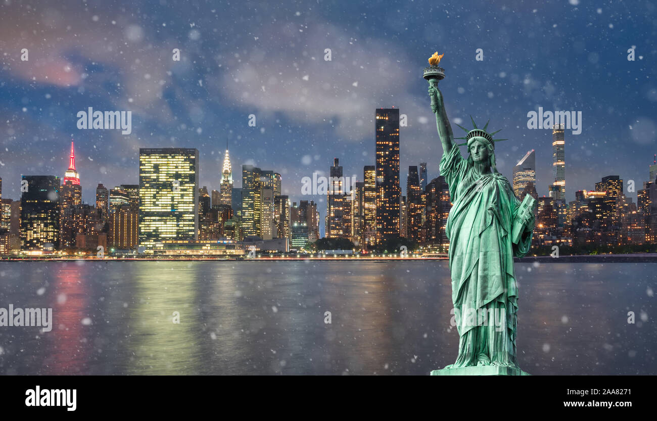 Statue of liberty in front of Manhattan skyline, at night, with snow Stock Photo