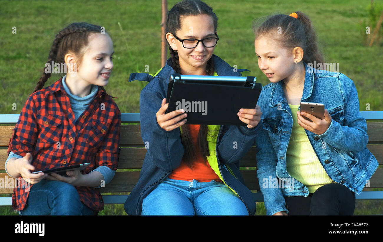 A group of children sitting on a bench and look at the tablet Stock ...