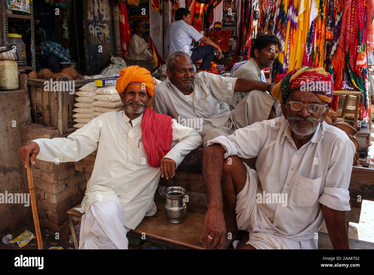 Bikaner, Rajasthan, India: four Indian men happy smile while sitting in front of a textile shop Stock Photo