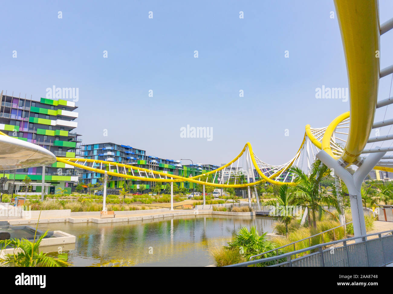 Gold Coast Australia - November 19 2019; Yellow wave-like architectural feature around pond with modern green and blue designed apartment buildings1 Stock Photo