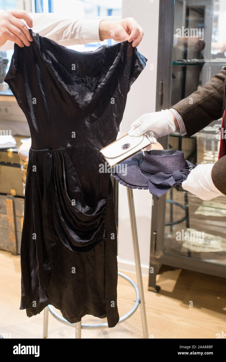 Grasbrunn, Germany. 20th Nov, 2019. Employees of the auction house smash a cocktail  dress made of black silk (l-r), a partially painted leather wallet and a  black and blue straw hat by