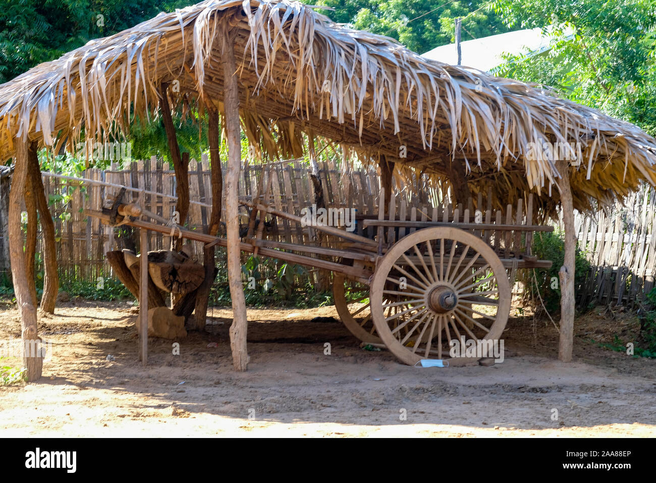Traditional Burmese ox cart made of wood and protected from the the weather under a straw covered shed in a village outside Bagan, Myanmar (Burma) Stock Photo