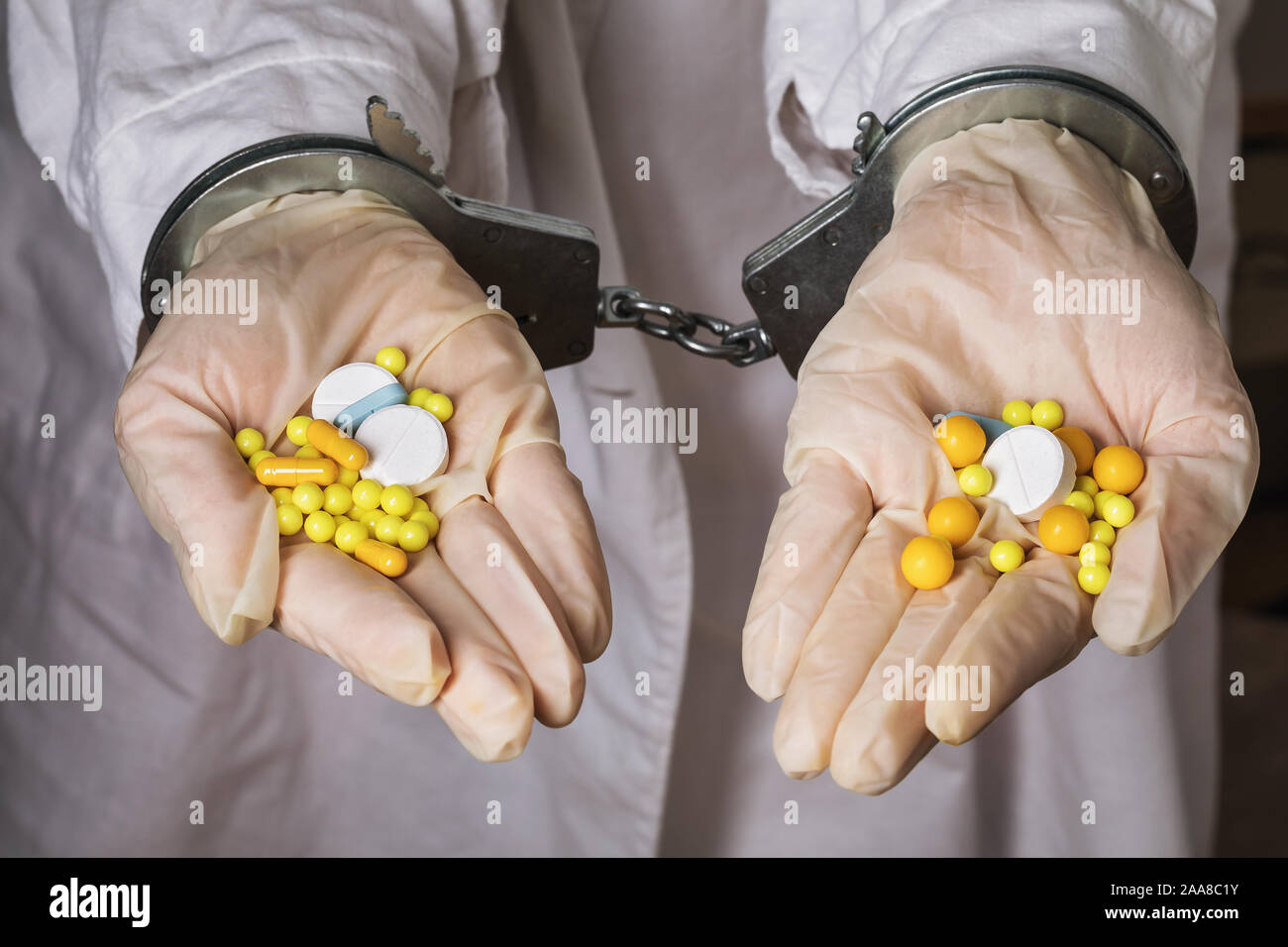 The detention of workers in the illicit manufacture of medicines. Hands holding pills are handcuffed Stock Photo
