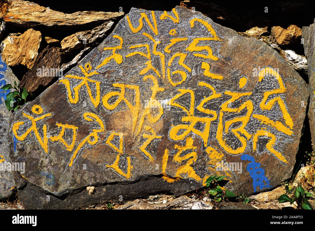 Carved mane-stone carrying the Buddhist message "Om mane Padme hom" by the side of a trail in east Nepal Stock Photo