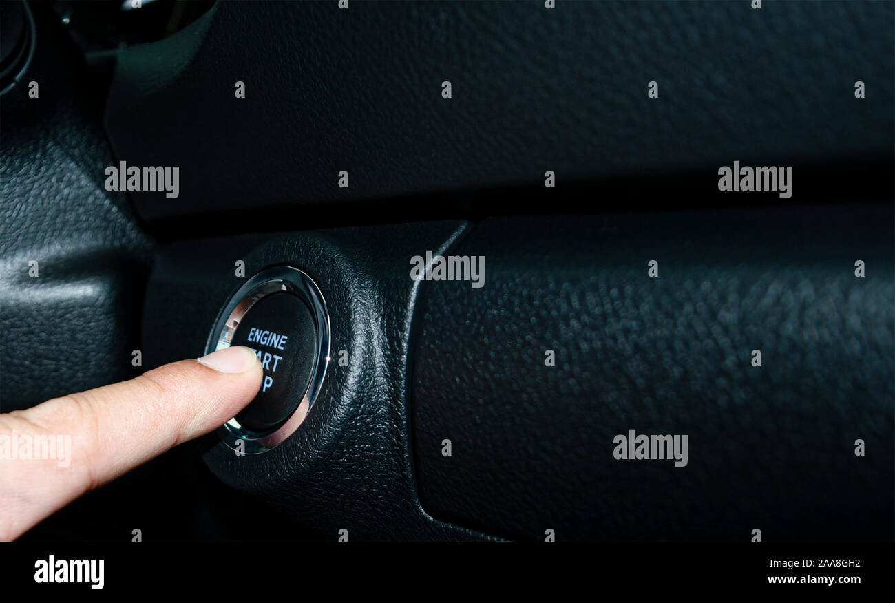 Car start stop system with finger pressing the button, horizontal image Stock Photo