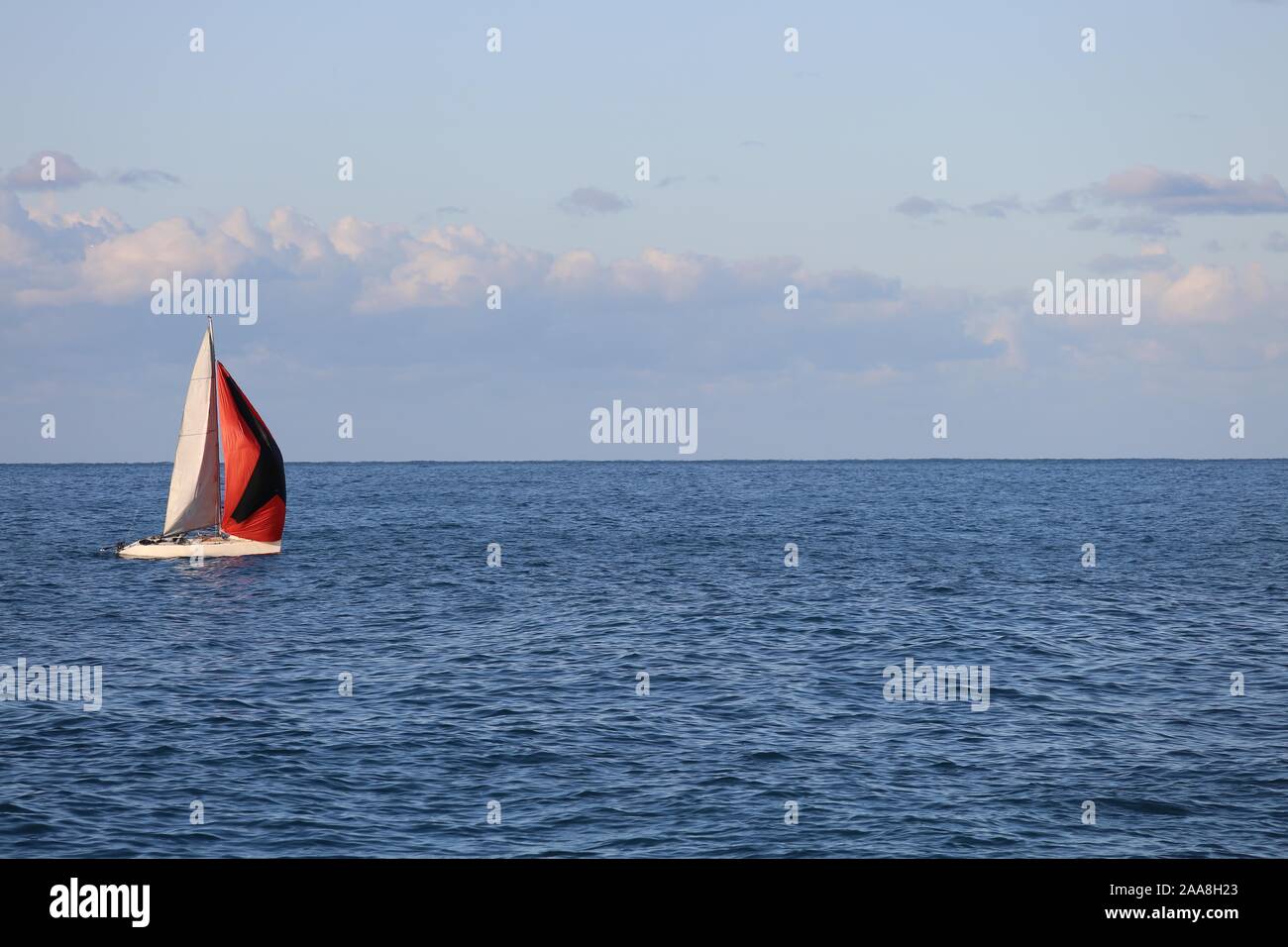 Red and white sailing boat on blue sea Stock Photo