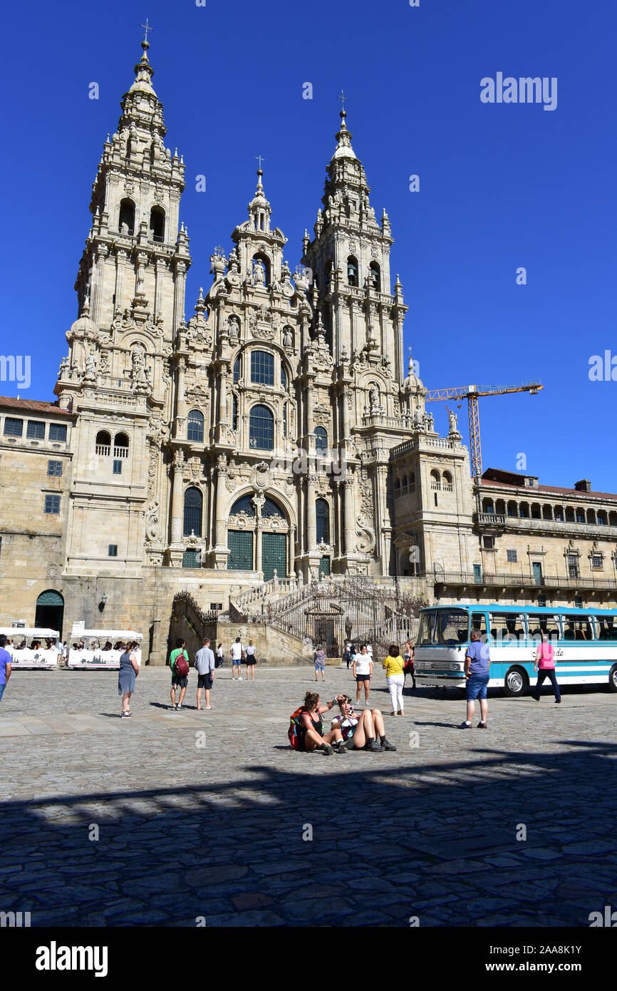 Cathedral with pilgrims taking pictures at Plaza del Obradoiro with old bus from exhibition. Santiago de Compostela, Spain. July 28, 2019. Stock Photo