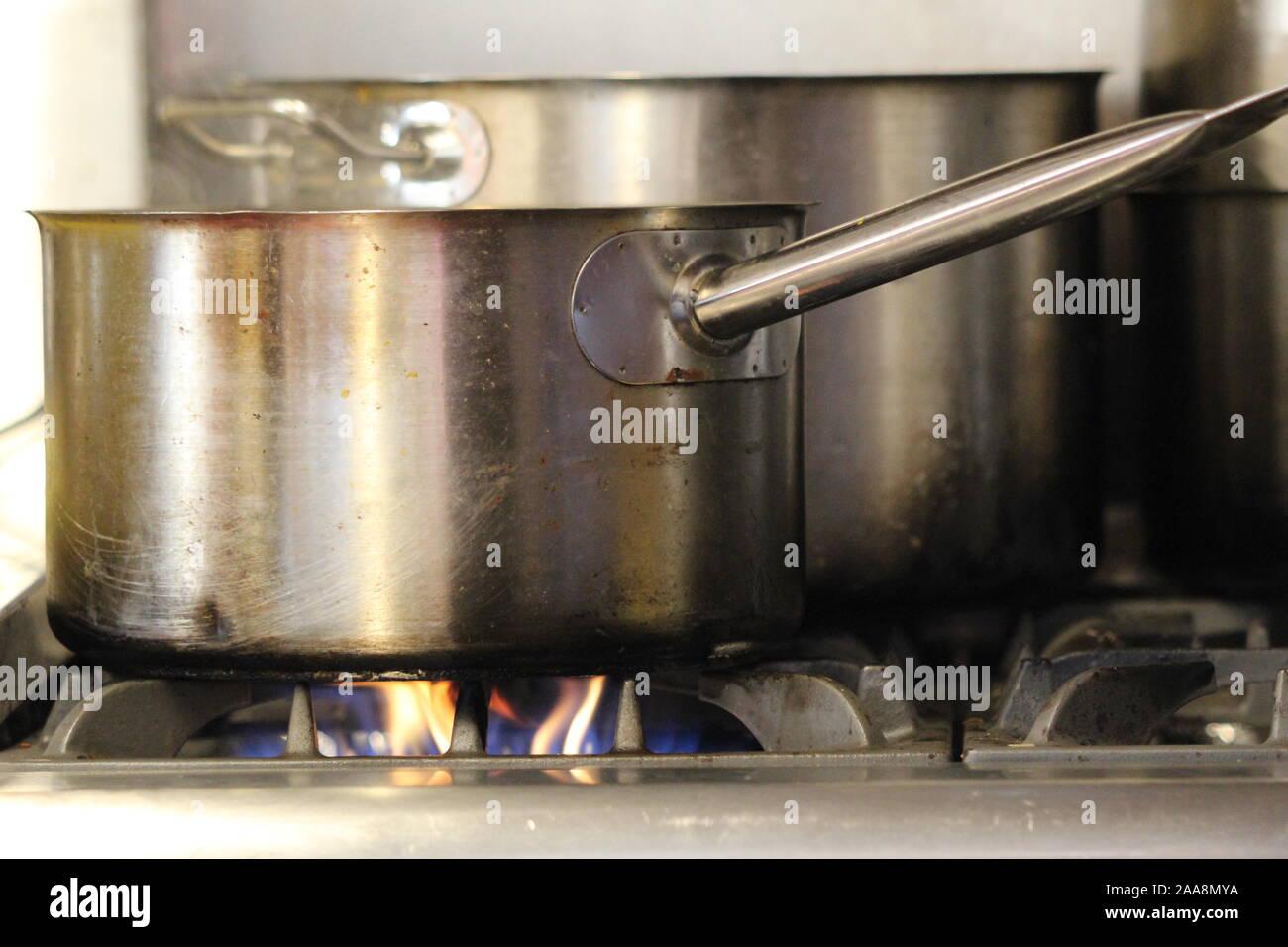 Pots and a pan on a gas stove with flame on Stock Photo Alamy