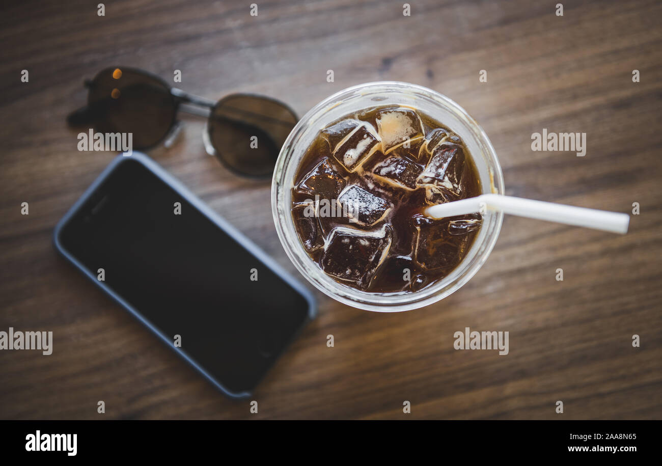 Ice americano coffee in plastic glass on wooden table with indoor warm ...