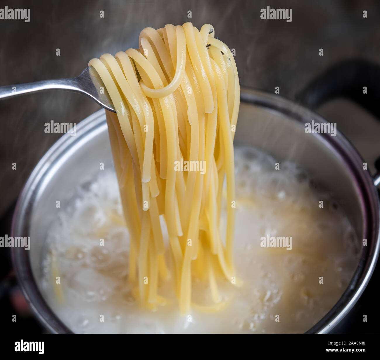 Yellow noodles or spaghetti cooking in boiling water pot with indoor