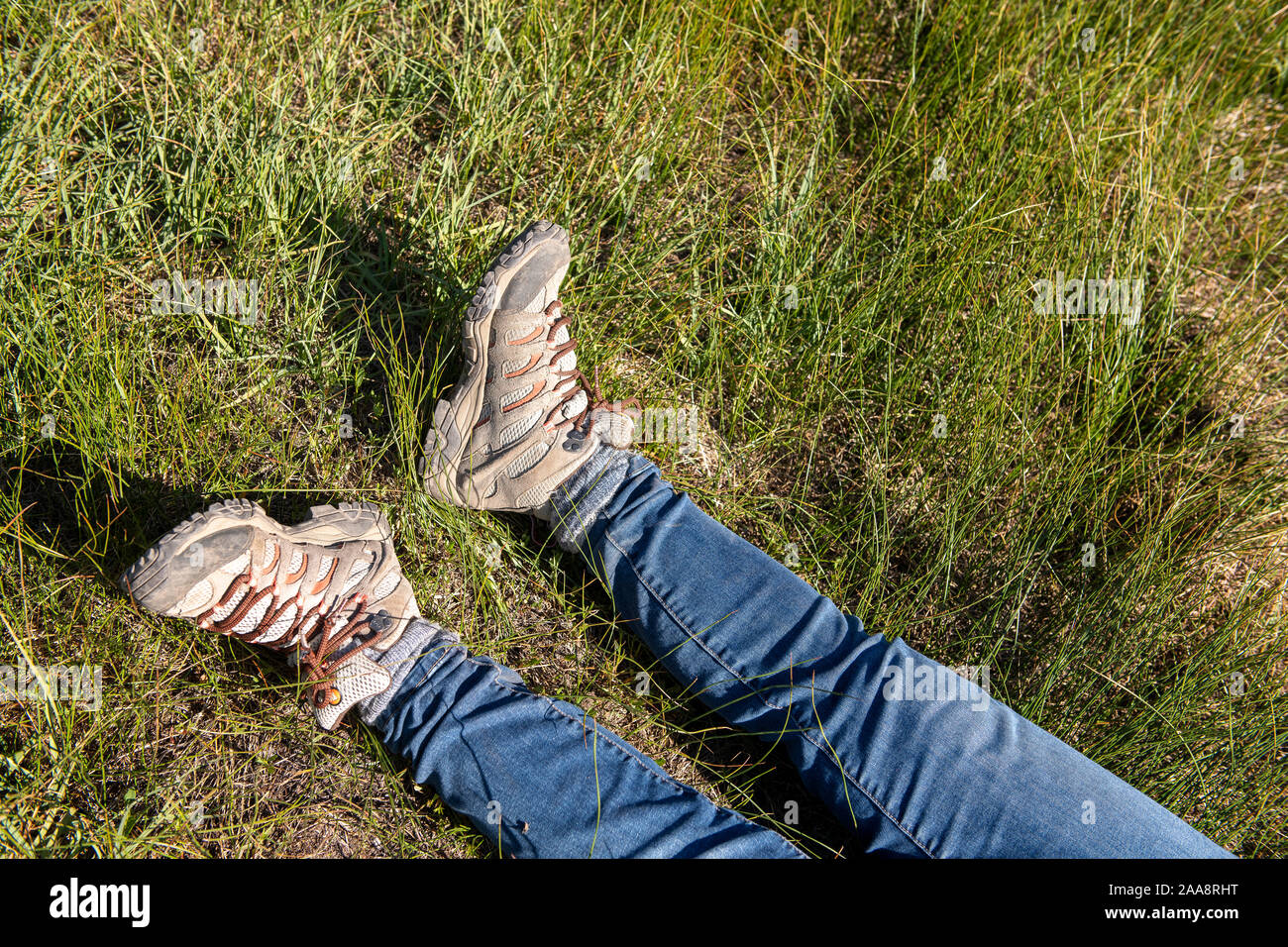 Legs in jeans and hiking boots laying in tall green grass Stock Photo
