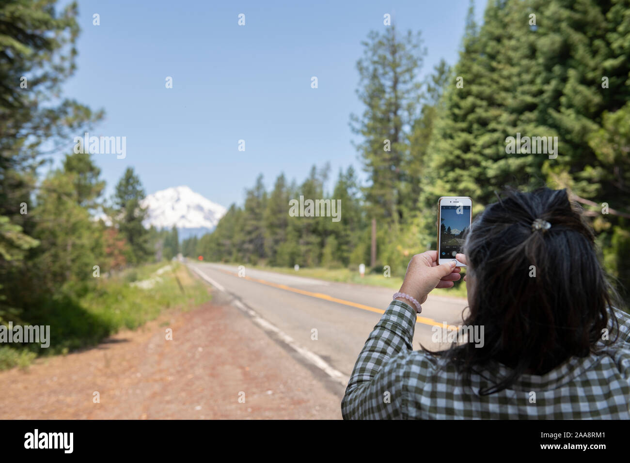 Woman roadside taking picture of Mount Shasta on her phone Stock Photo
