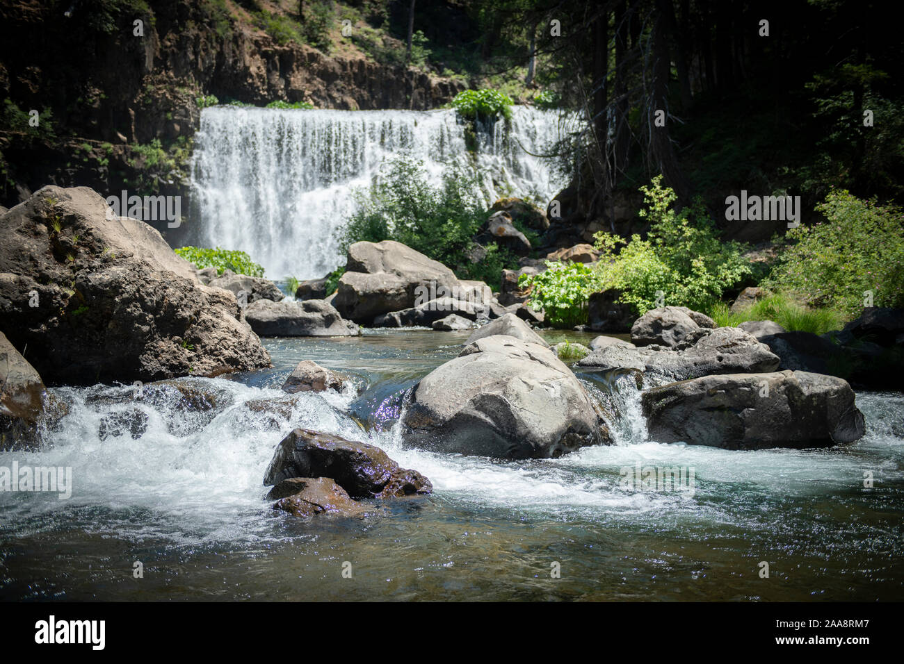 Rocky creek with wide low waterfall in the background Stock Photo