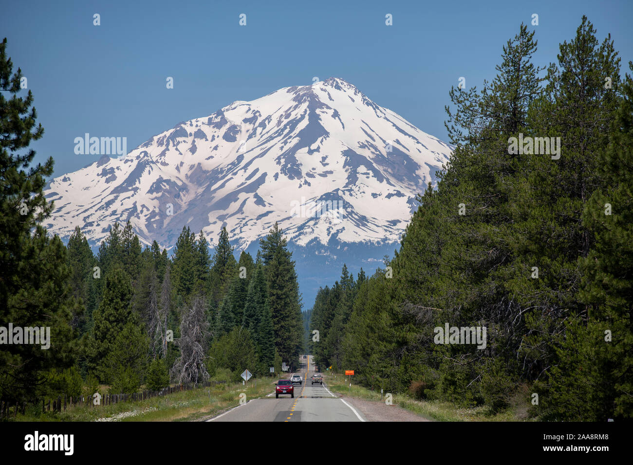 Cars on a two lane highway 89 leading to snow covered Mount Shasta Stock Photo