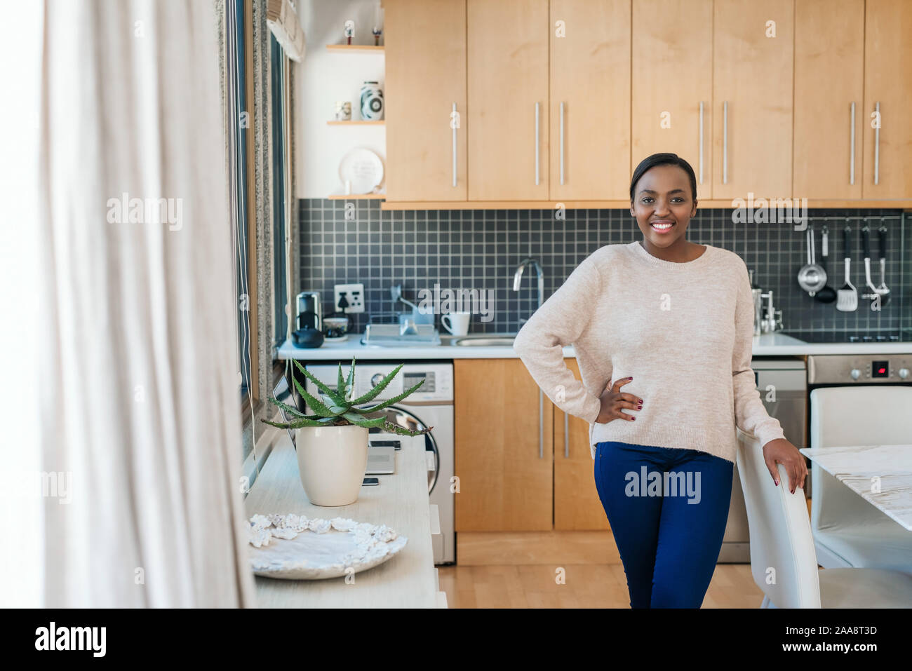 Smiling young African American woman standing in her apartment Stock Photo
