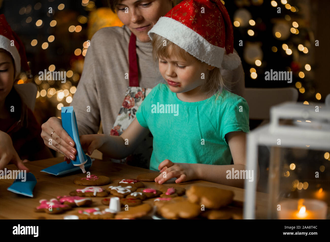 Mother And Little Kids In Red Hats Cooking Gingerbread Cookies And