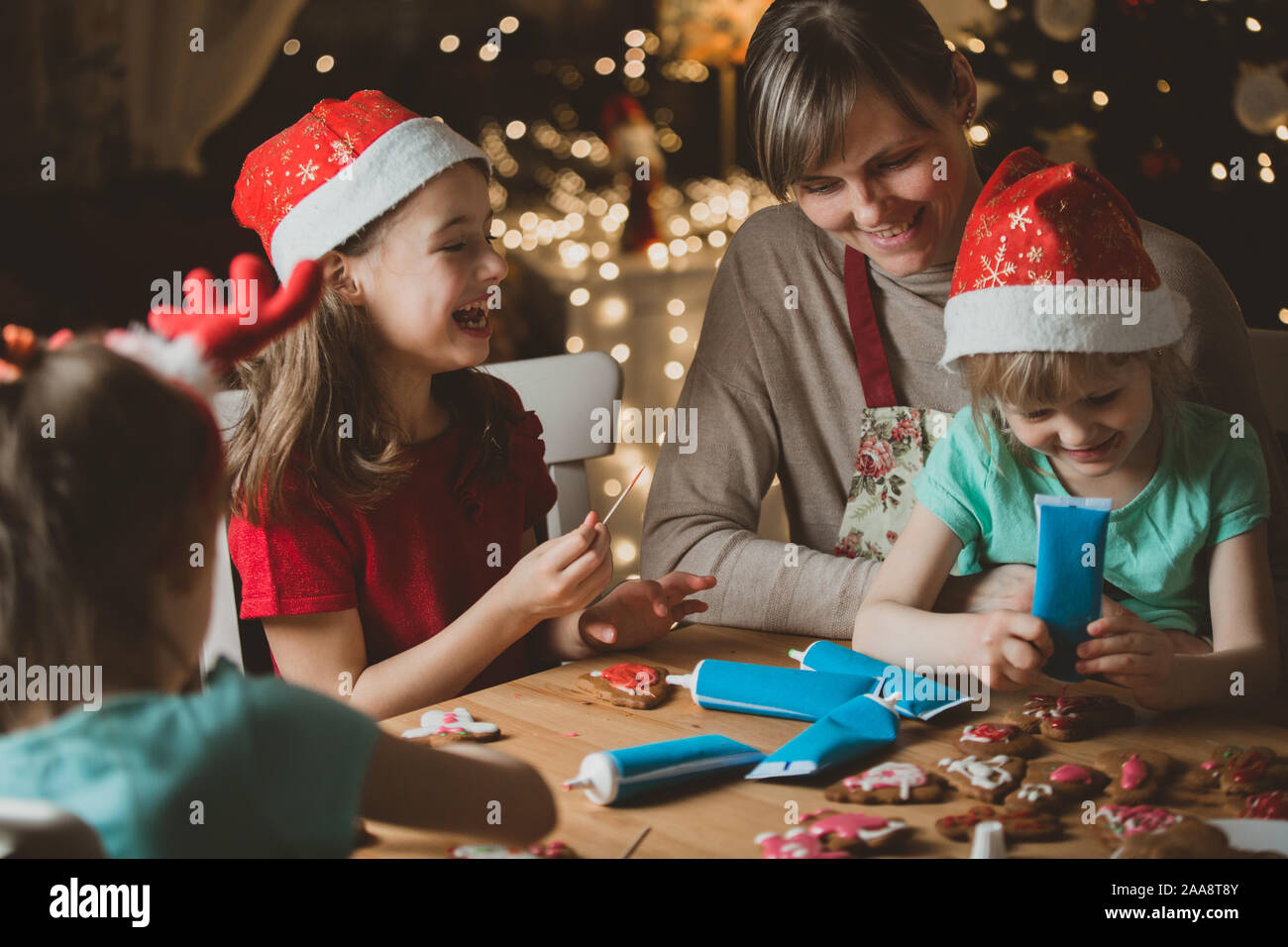 Mother And Little Kids In Red Hats Cooking Gingerbread Cookies And