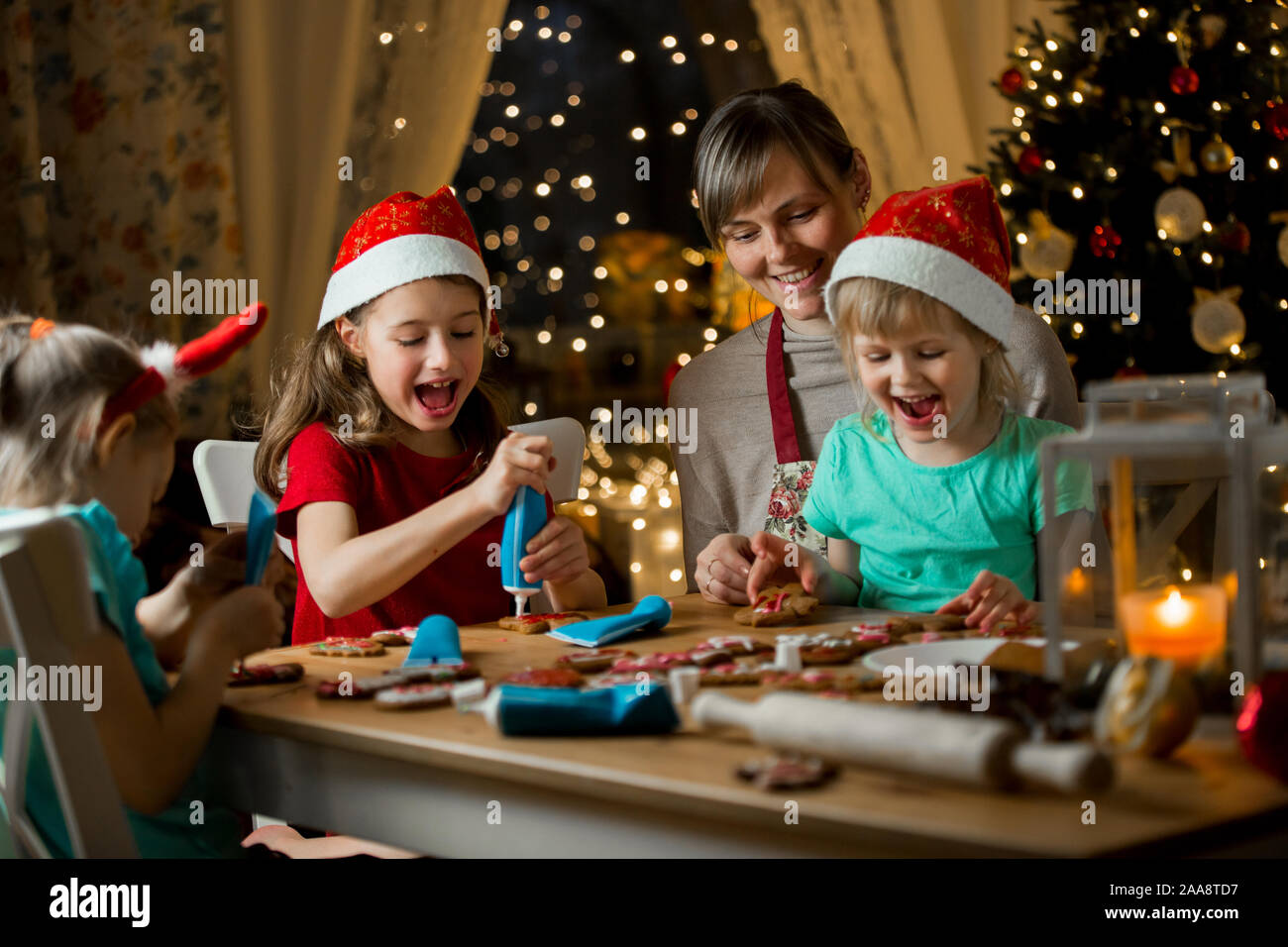 Mother And Little Kids In Red Hats Cooking Gingerbread Cookies And