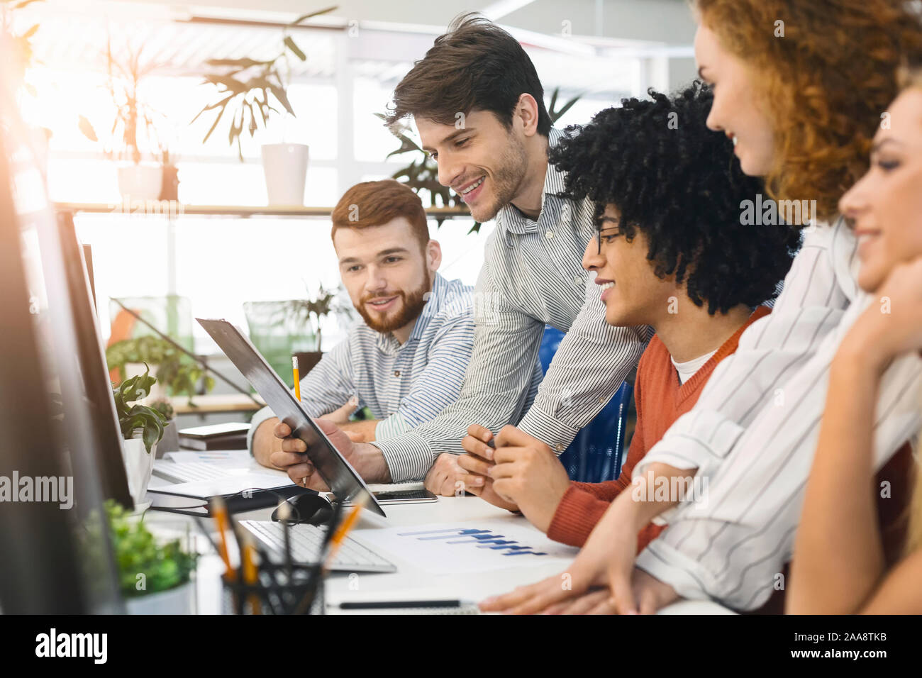 Young team analyzing information on computer screen in office Stock Photo