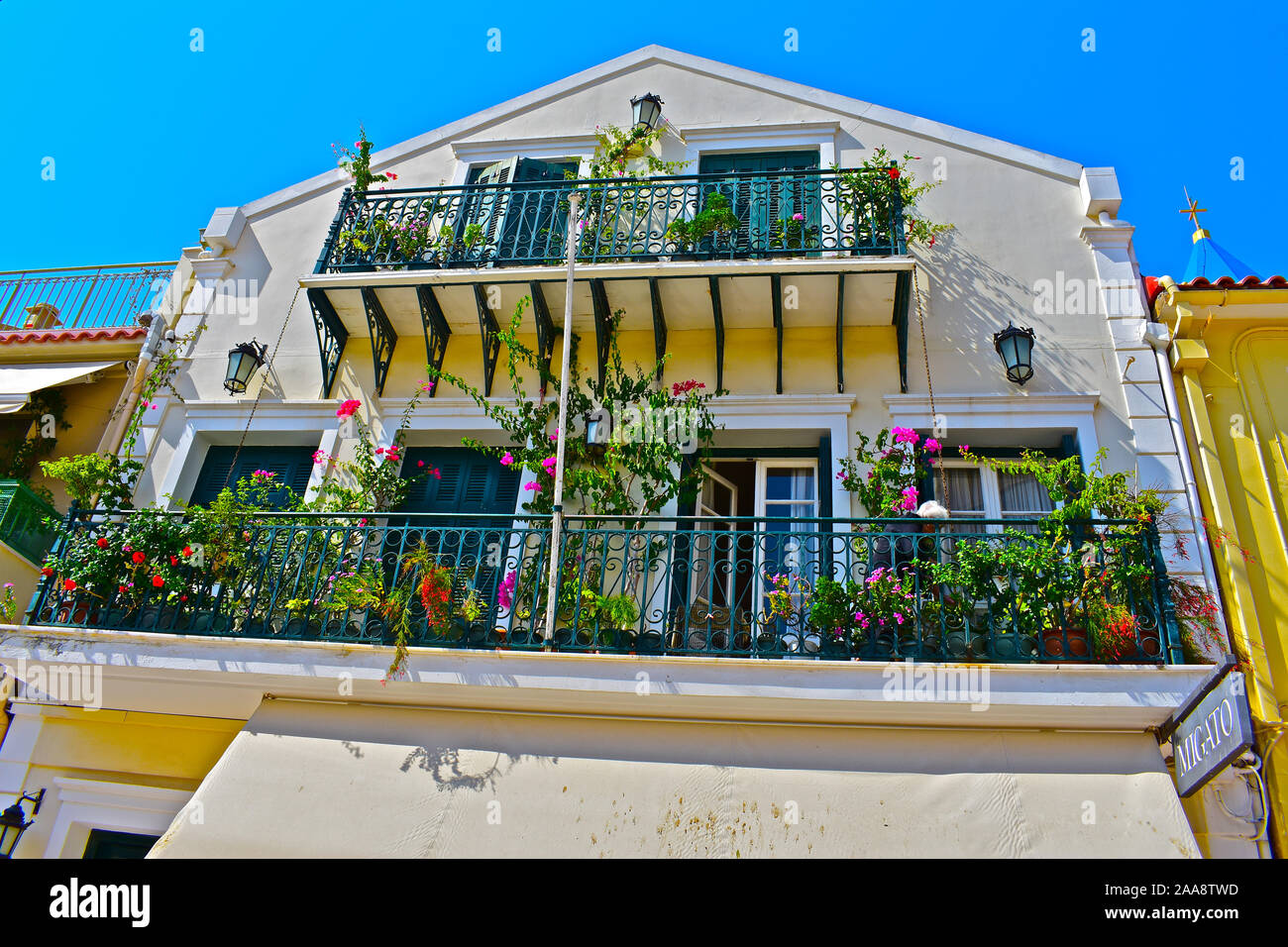 An old lady tending her flowers & plants on the balconies above the Migato  fashion shop in Lithostroto, the main street in the centre of Argostoli  Stock Photo - Alamy