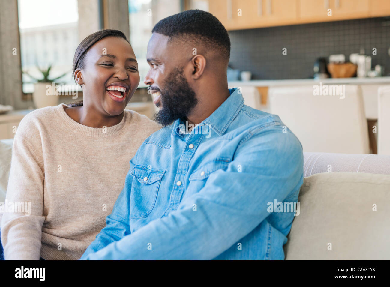Young African American couple sitting on their sofa and laughing Stock ...