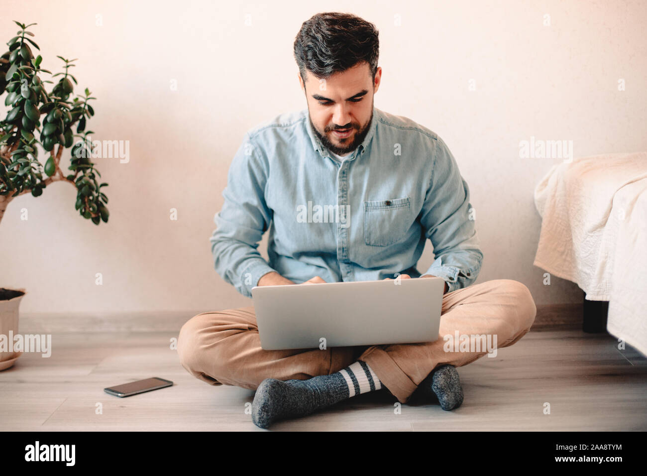 Young man using laptop computer while sitting on floor at home Stock Photo