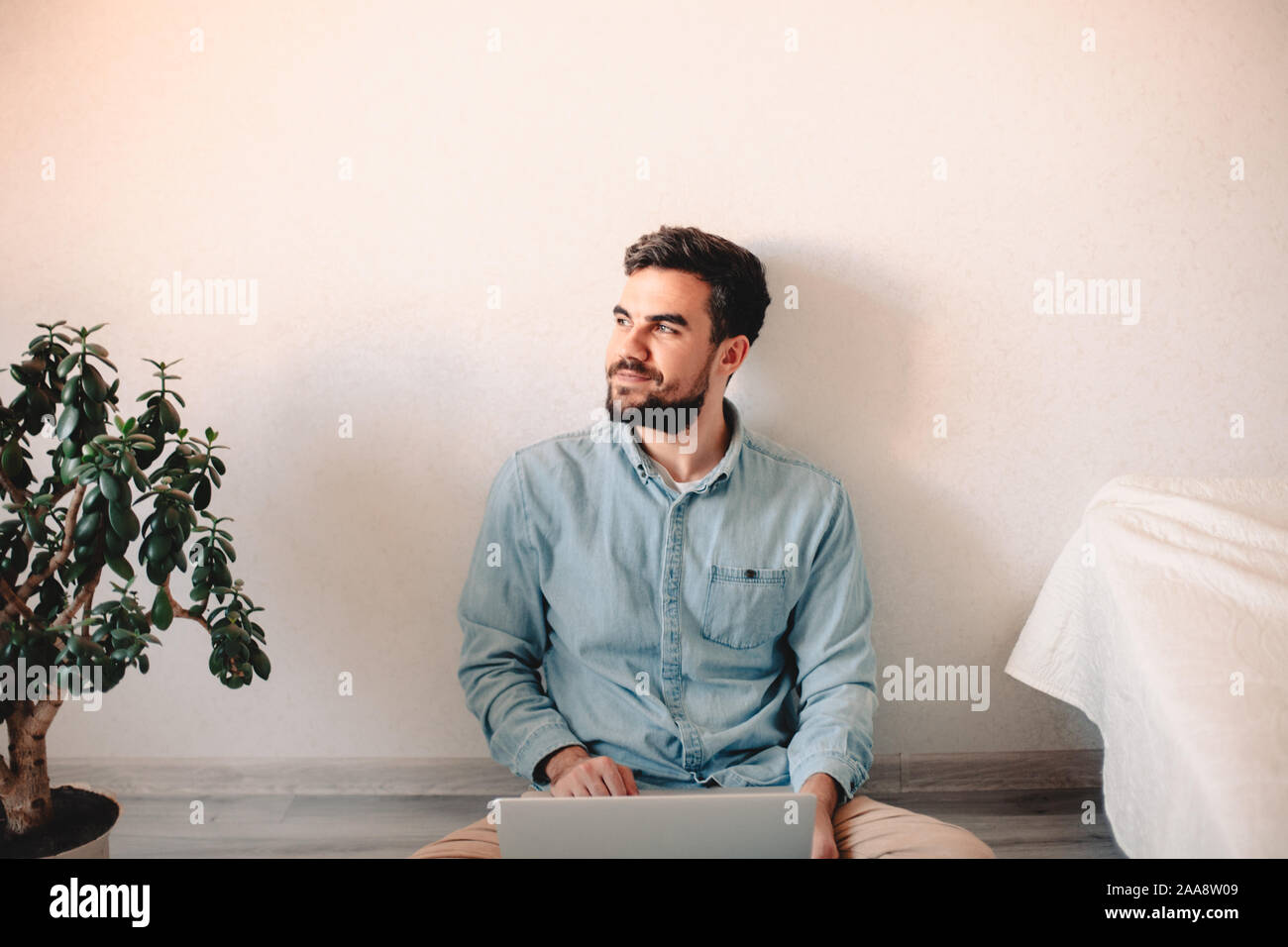 Happy businessman using laptop computer while sitting on floor at home Stock Photo