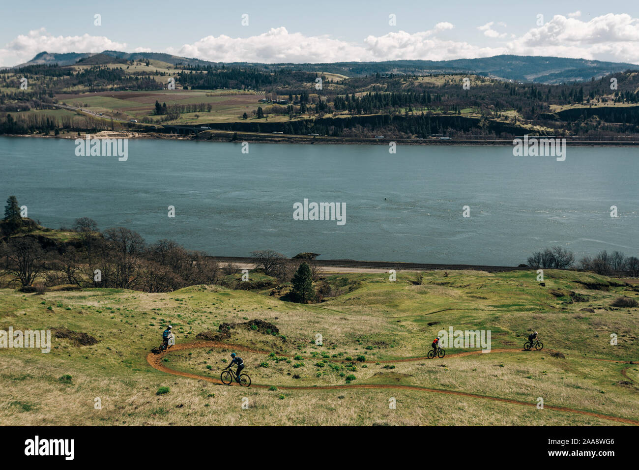 A group of girls bike along a trail overlooking the Columbia River. Stock Photo