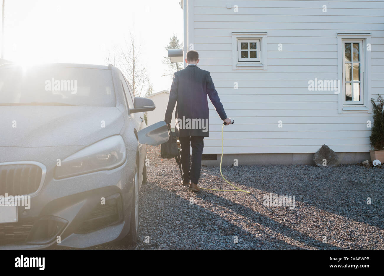 man walking with electric car lead leaving for work in the morning Stock Photo
