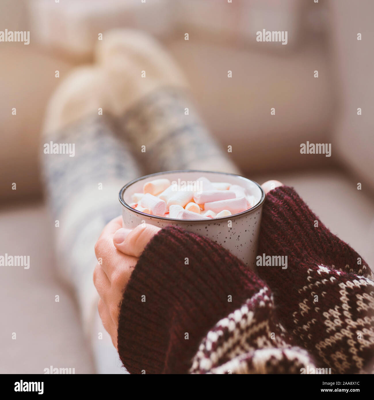 Woman in warm sweater with patterns and funny socks drinking hot chocolate Stock Photo