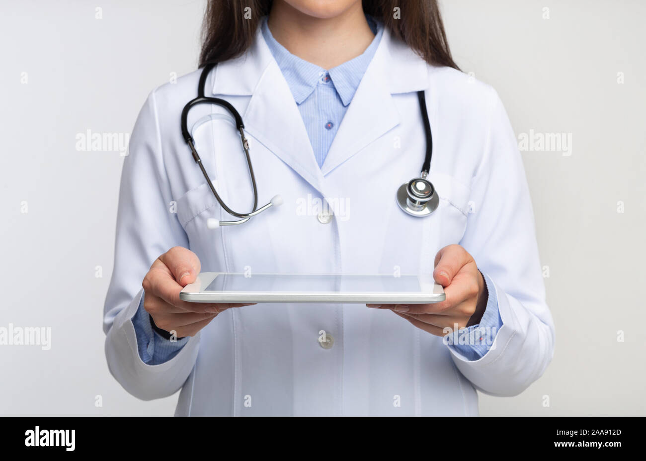 Unrecognizable Lady Doctor Holding Tablet Computer Standing, White Background, Cropped Stock Photo