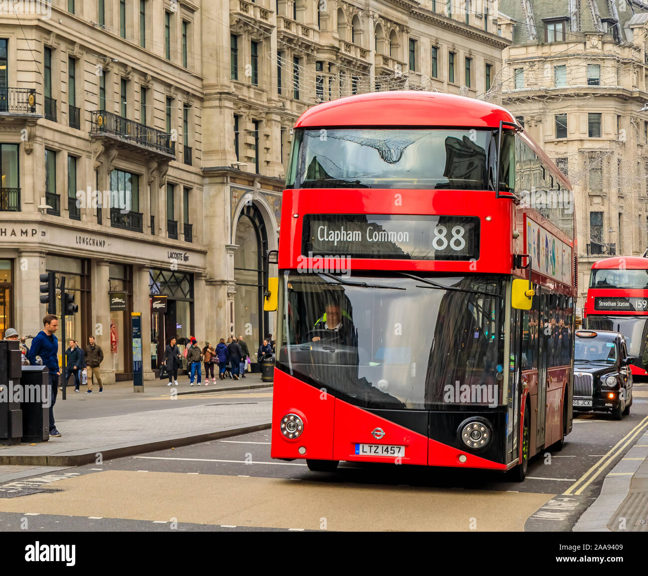 London, United Kingdom - January 13, 2018: Luxury stores on Regent street with people passing by and a double decker red buss on the road Stock Photo