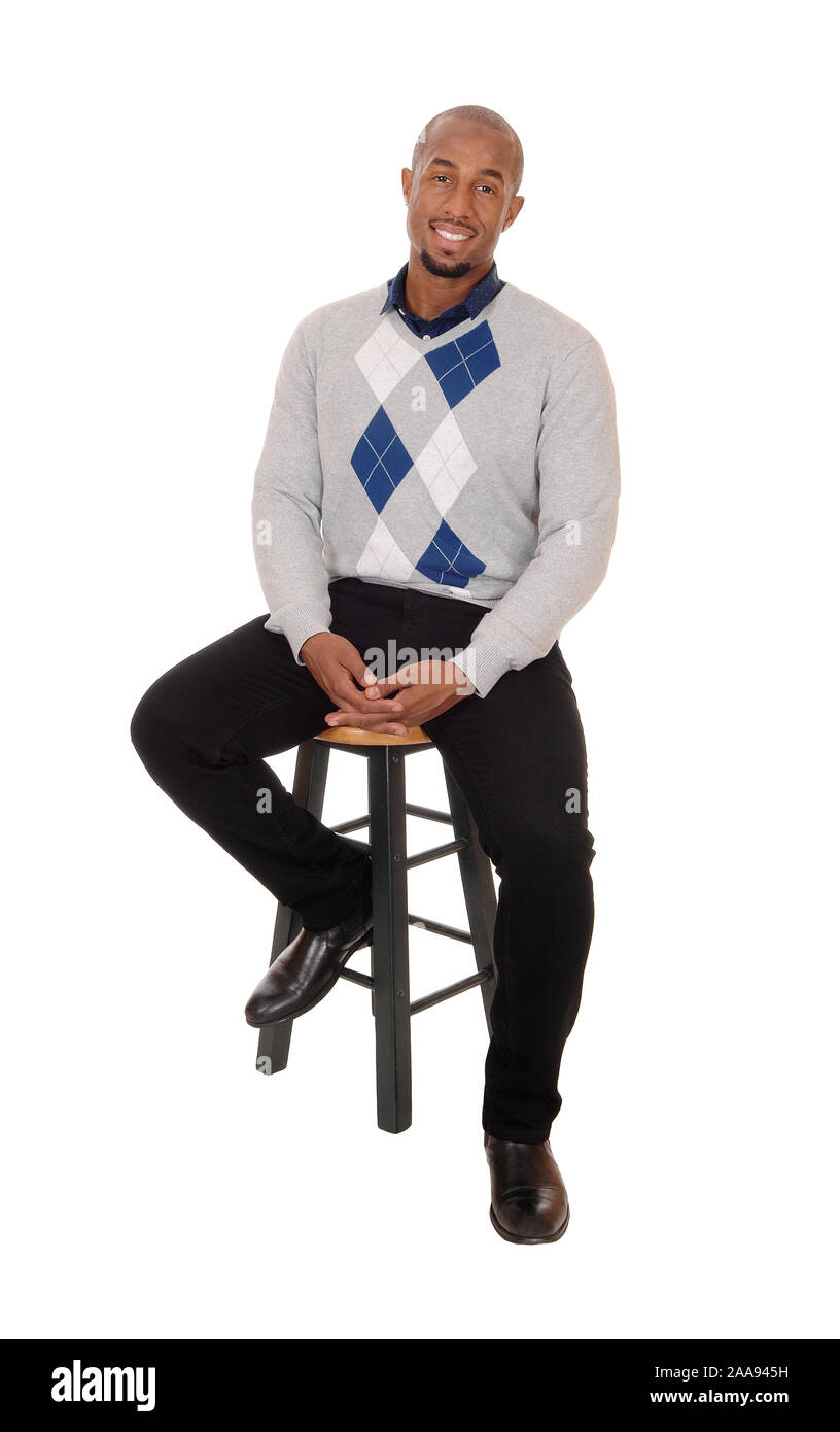 A young handsome African American man sitting full body in the studio, thinking and smiling, isolated for white background Stock Photo