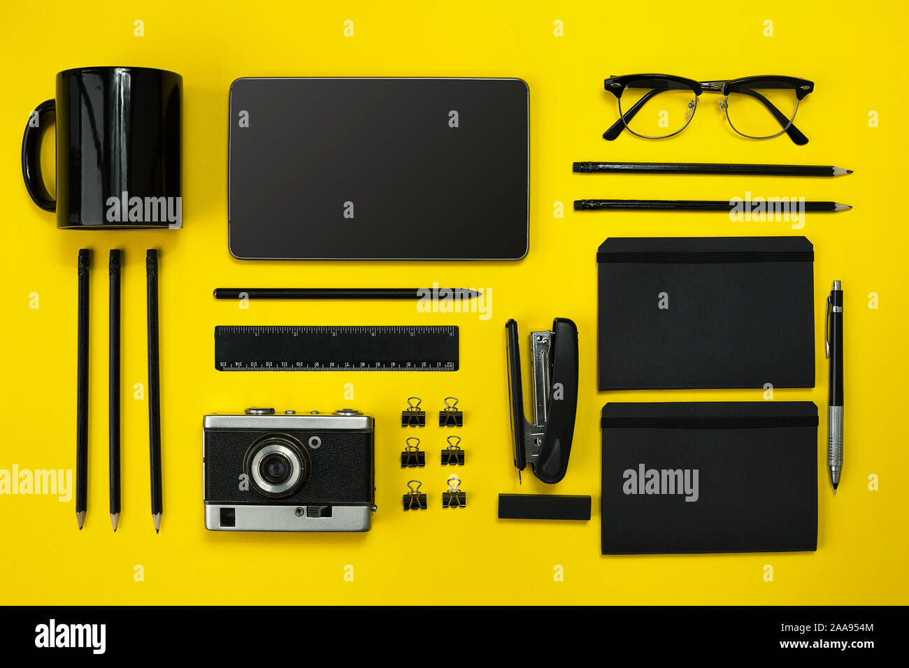Black objects from the office on a yellow background. Work and creativity. Social media concept hero header image. Top view. Still life. Copy space Stock Photo